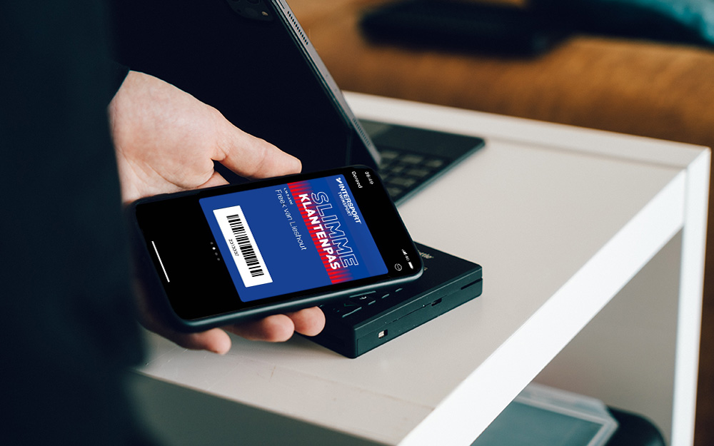 Eine Frau scannt ihre digitale Apple Wallet Kundenkarte an der Kasse. Damit nimmt sie am Treueprogramm des Einzelhändlers teil.